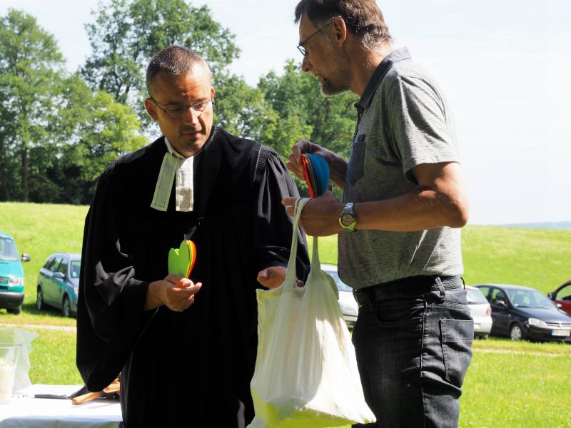 Pfarrer Grünwedel und Wolfgang Schwanecke verteilen Papierherzen und Kugelschreiber an die Gemeinde.